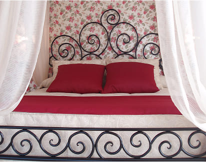 Cama de forja negra con cabecero y piecero decorativos de estilo clásico