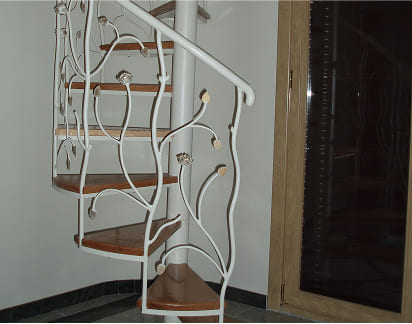 Escalera de caracol con barandilla de forja decorada con motivos vegetales