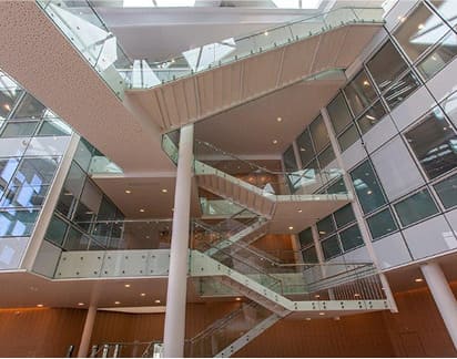 Escaleras interiores con estructura metálica y barandillas de vidrio en edificio de oficinas