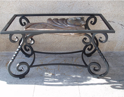 Mesa de forja artística con estructura decorativa y sobre de cristal