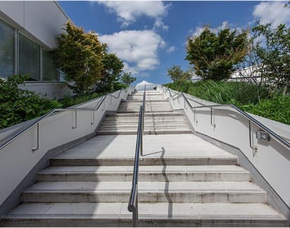 Escalera exterior con pasamanos de acero inoxidable en entorno ajardinado