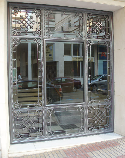 Peurta de entrada en forja artística con detalles ornamentales en edificio residencial