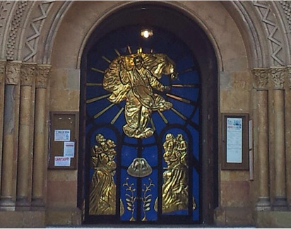 Portón artístico religioso en forja y latón dorado en entrada de iglesia