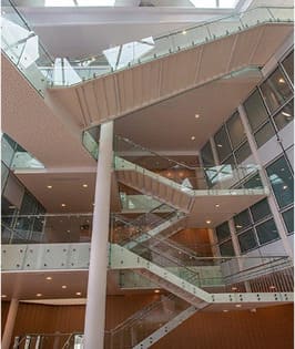 Escalera estructural metálica con barandillas de vidrio en edificio corporativo